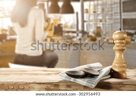 blurred background of bar with woman on chair and two wooden spoons on napkin