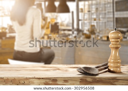 blurred background of bar with woman on chair and two wooden spoons on desk top