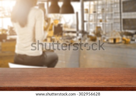 blurred background of bar with woman on chair and wooden glasses desk top