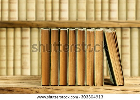 desk with retro old books in golden color and brown wall of retro books