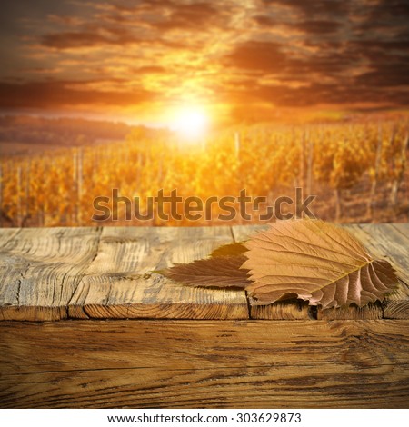 autumn sunset and landscape with big autumn leaf and wooden desk top
