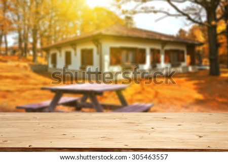 blurred background of autumn and yellow wooden desk space and sun in garden and garden table