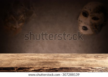 blurred background of wall with carnival mask and dirty shabby wooden brown desk space