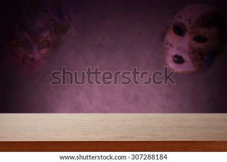 blurred background of wall with carnival mask and dark brown desk space