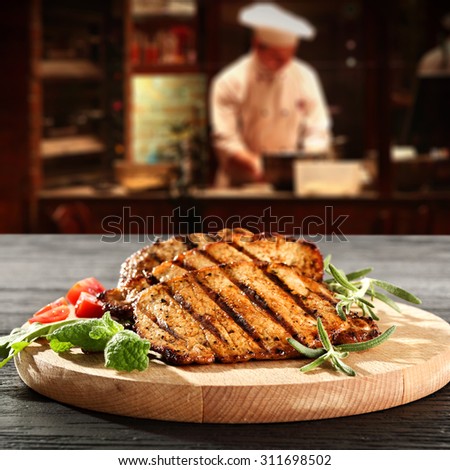 interior with cook of restaurant kitchen and steak on wooden desk top