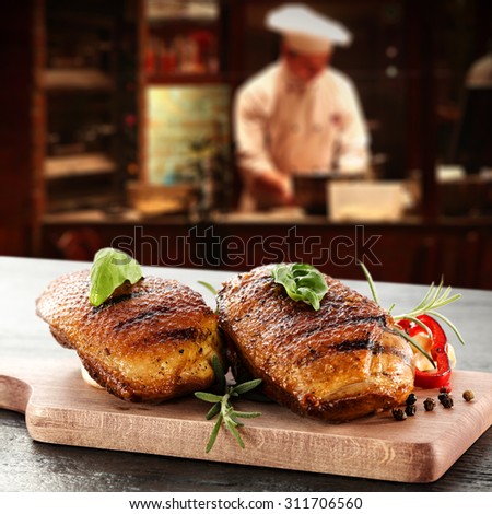 young cook in kitchen interior of bar and golden duck meat