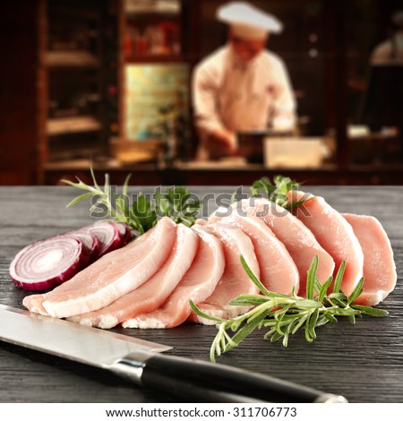 young cook in kitchen interior of bar and raw meat of chicken  and knife