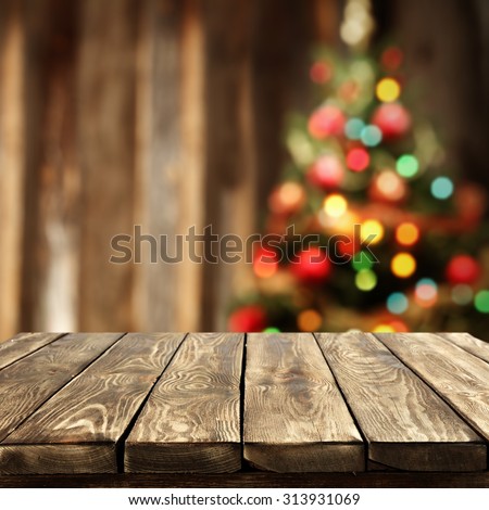 blurred background of xmas tree lights and wall with table of brown color