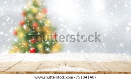 Wooden table place. Space for your decoration. Snow on top of board. Christmas tree on background.