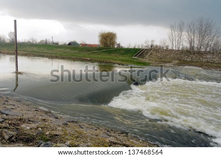 Flooded river with rural landscape with stormy  sky