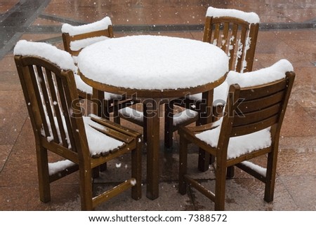 First snow of the season covers a wooden table and chairs