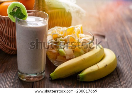 Banana smoothie with fruit salad and two bananas on a wooden table