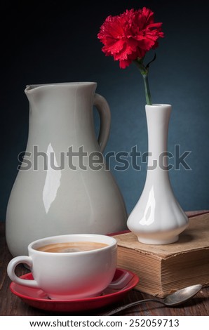 still life carnations in vase and coffee and jug on dark background