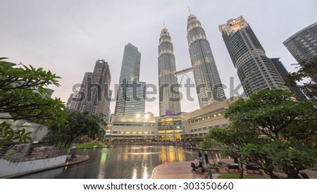 KUALA LUMPUR, MALAYSIA - AUGUST 1, 2015: Water Fountain at Suria KLCC with Petronas Towers and Office Buildings at Blue Hour sunset at Night. It\'s a popular shopping attraction to locals and tourists.