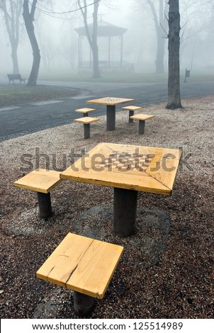 Wide angle captured chess table in the park with bandstand in foggy  background
