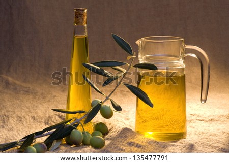 Jar and bottle of olive oil with olive branch on burlap background