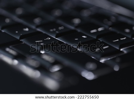 Closeup up of backlit computer laptop keyboard selective focus on question mark key ideal for technology support night hacker standout