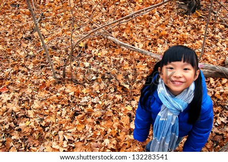 Happy little girl in the maple leaves forest during autumn(Canada)