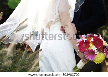 bride and groom holding each other with veil blowing in the wind