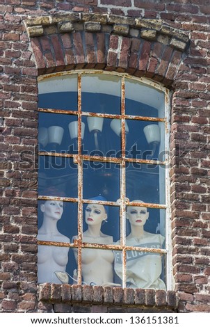 Mannequins behind a window looking out