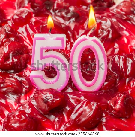 Cherry cheese cake with burning candles for 50th birthday