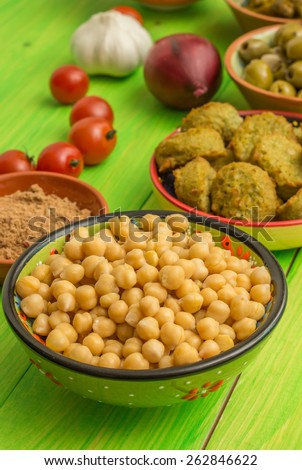 Chick peas, falafel, spices and vegetables on a green table