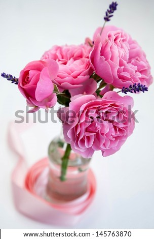 Small pink rose bouquet with lavender in a bottle on white background