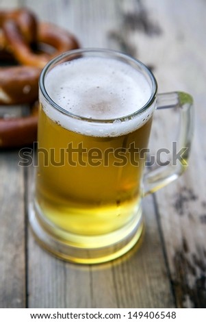 Mug fresh beer with pretzels on wooden table