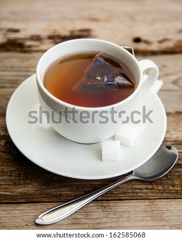 Cup of freshly brewed earl grey tea with sugar cubes on wooden table
