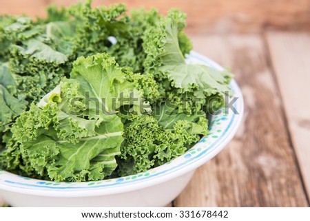 Raw kale in a beautiful bowl on wooden table, ready for making kale chips or ready to cook