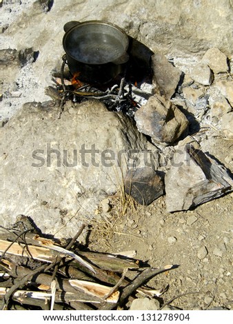 Cauldron outdoors / Cauldron with boiling water over bonfire outdoors with rocky and woody natural background