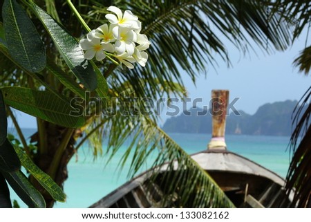 Paradise Thailand / Beautiful Thailand islands shot of the long-tailed boat overlooking the blue ocean, with monoÃ?Â¯ flowers and palm leafs on the fore-scene