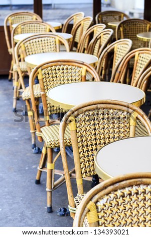 Sidewalk cafÃ?Â© in Paris / Rattan-style wicker cafÃ?Â© chairs and typical circular tables of the typical Parisian coffee-house