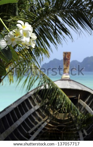 Beautiful Thailand islands shot of the long-tailed boat overlooking the blue ocean, with monoÃ?Â¯ flowers and palm leafs on the fore-scene