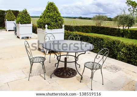 Open terrace with iron patio furniture and vineyard on the background, Gironde, France