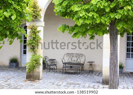 Open terrace with iron patio furniture by the house arched wall, Gironde, France