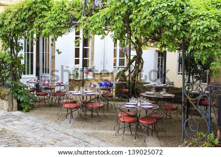 Open restaurant terrace under a grape vine in Saint-Emilion town, Gironde, France