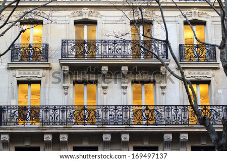 Building facade in Paris - windows just got lit warm yellow in the beginning of the evening.