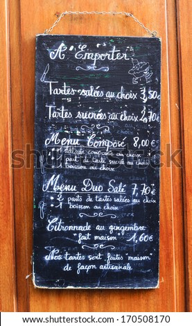 French cafe menu board handwritten in chalk on blackboard hanging on the wall at the sidewalk in Paris, France