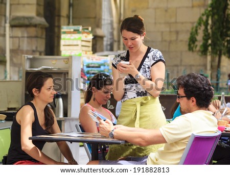 PARIS, FRANCE - JULY 28 : Young waitress taking an order from a tourist couple in an open cafe at Mouffetard street in central Paris on July 28th, 2014 in Paris, France