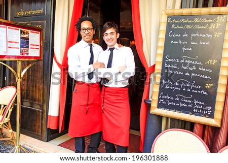PARIS, FRANCE - MARCH 12 : Two waiters of the french restaurant near Odeon in Paris posing together at the restaurant door by the menu board on March 12th, 2014 in Paris, France