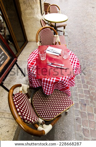 Paris - traditional french cafe with it\'s round tables with Parisian cafe table with checked napkinand chairs outdoors on the sidewalk, wide-angle lens