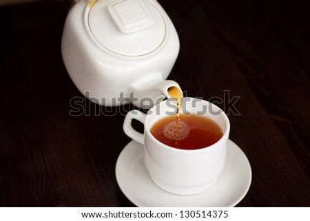 Tea time - white teacup and teapot on black background