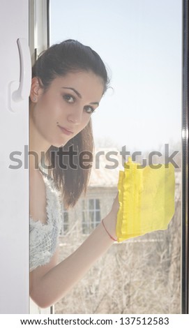 Young girl carefully washes and cleans a window