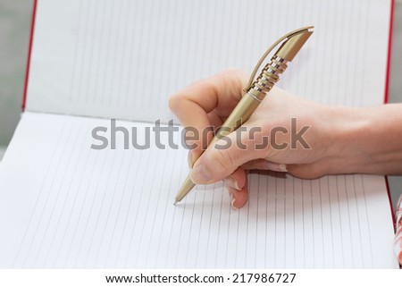 Human hand writes with a pen in a notepad