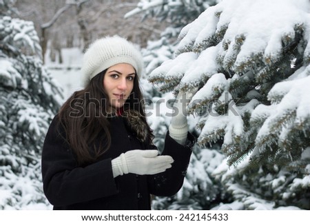 Cheerful beauty woman standing outside near a snow covered branch of a fir tree