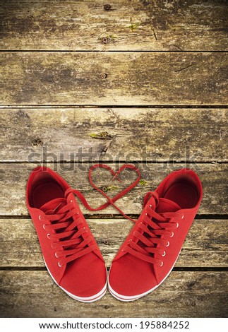 Heart-shaped red shoelaces of sneakers on wooden deck