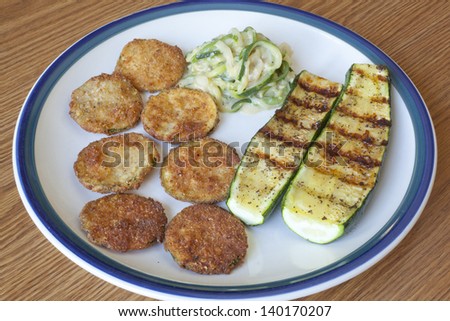 A plate of zucchini cooked three different ways, fried, grilled and a spaghetti zucchini with garlic sauce