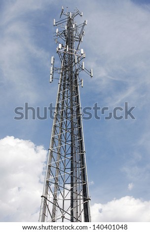A cell tower with a cloudy blue sky background