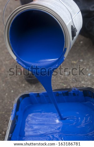 Pouring blue paint into a tray